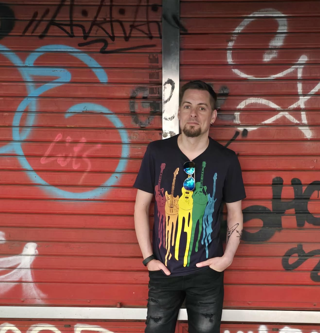 Ronny Trubadur foran rødt gjerde med graffiti