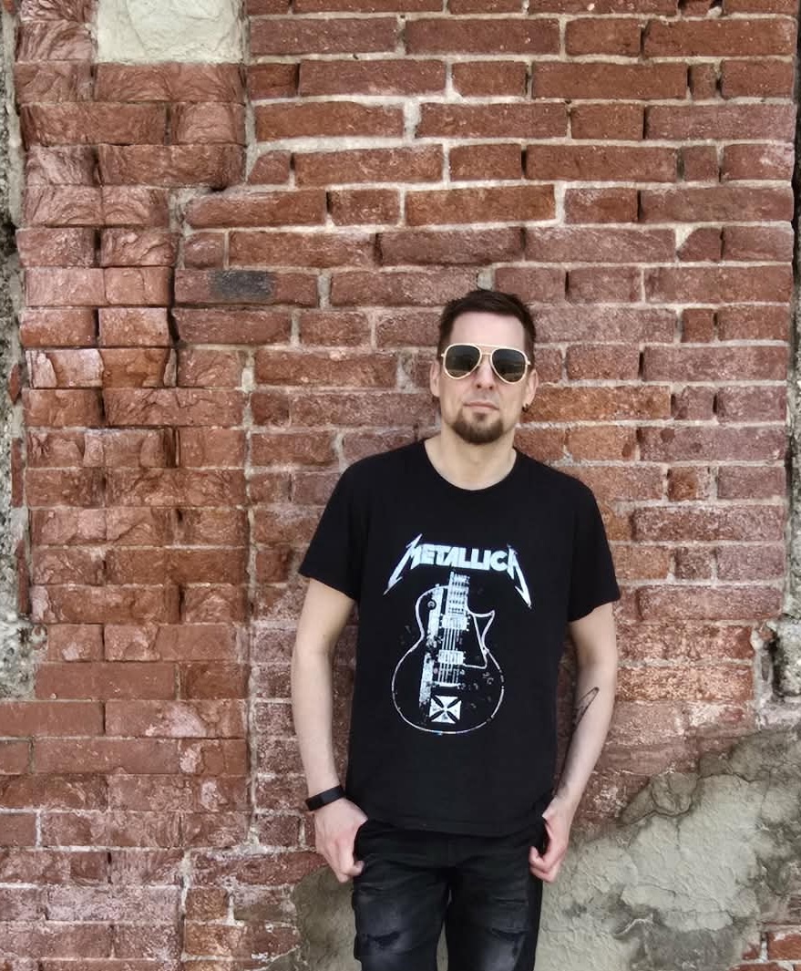 Ronny Trubadur i Metallica-skjorte mot murvegg